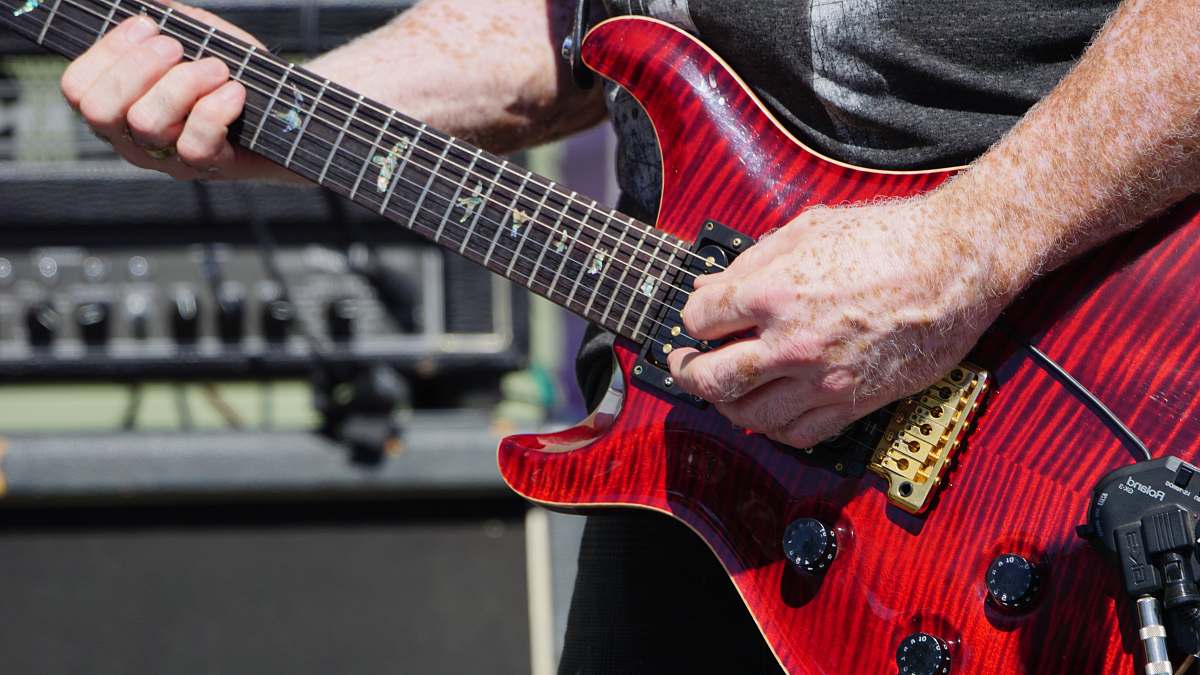 guitar person playing a red stratocaster guitar during daytime leisure activities